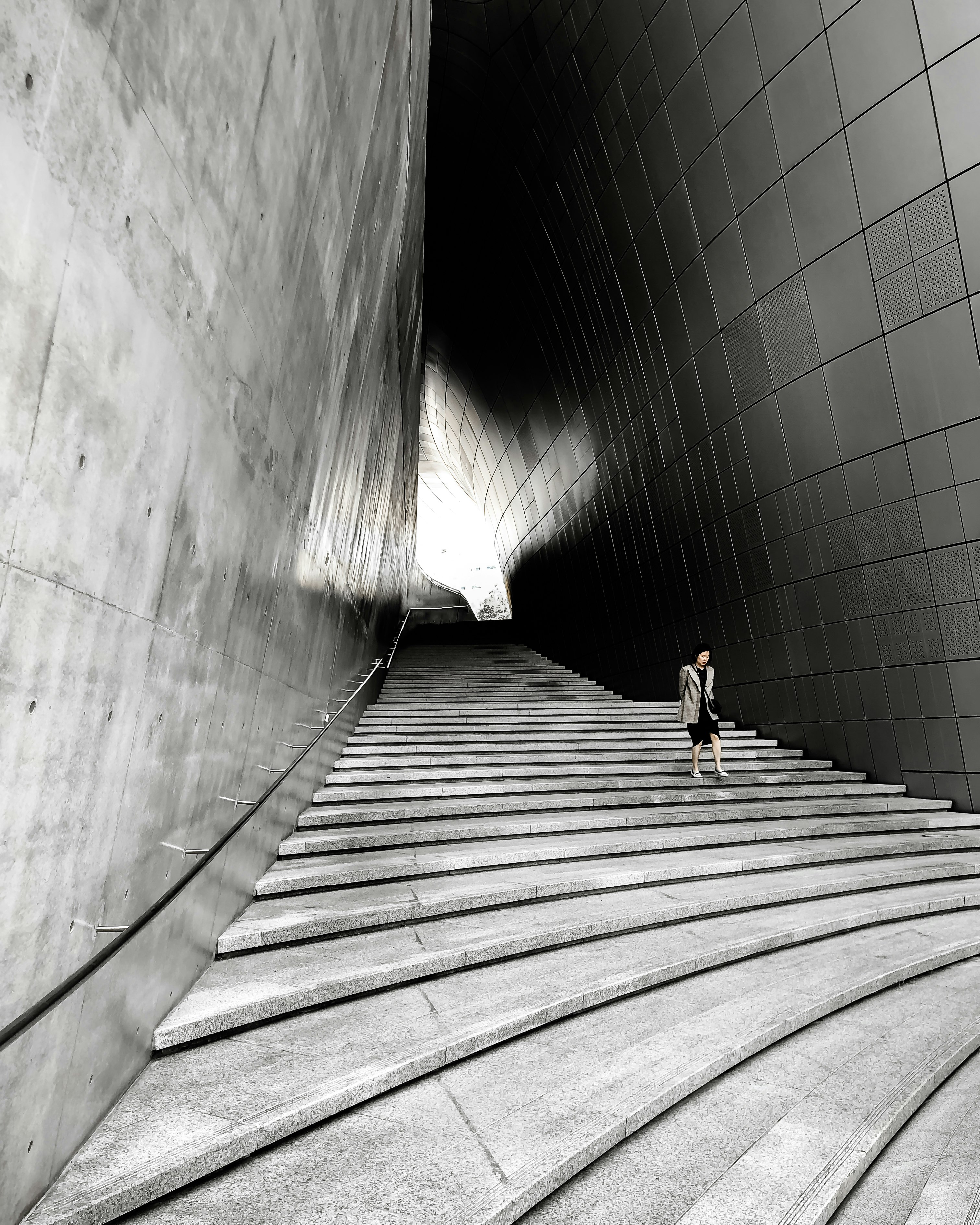 woman in black shirt walking on gray concrete tunnel